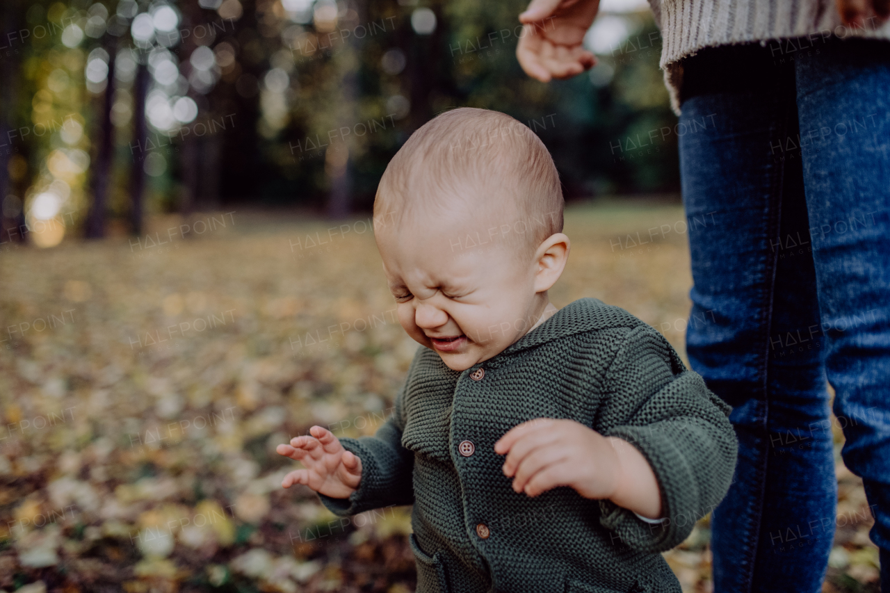 A mother with her little baby son wearing knitted sweater during walk in nature, close-up