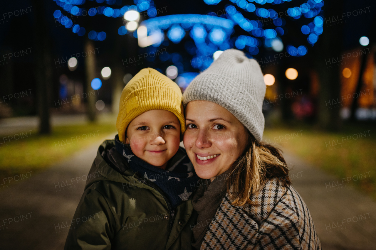 Portrait of happy young mother with her little cute son at outdoor christmas market, cosy atmosphere.