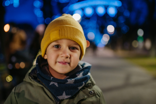 Portrait of little boy in winter clothes at outdoor christmas city market.