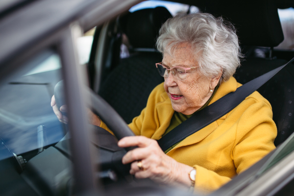 Focused senior woman driving car alone, holding the steering wheel firmly. Safe driving for elderly adults, older driver safety.