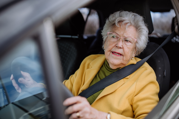 Focused senior woman driving car alone and enjoying car ride. Safe driving for elderly adults, older driver safety.