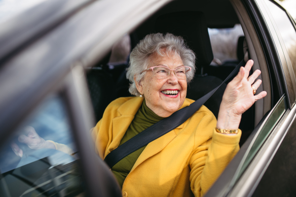 Happy senior woman driving car alone, enjoying the car ride. Safe driving for elderly adults, older driver safety. Driving license renewal at older age.