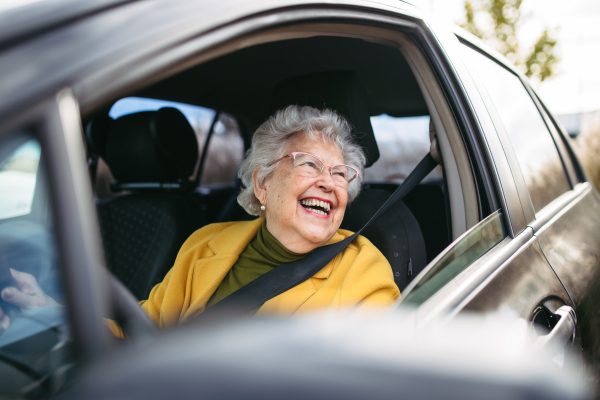 Happy senior woman driving car alone, enjoying the car ride. Safe driving for elderly adults, older driver safety. Driving license renewal at older age.