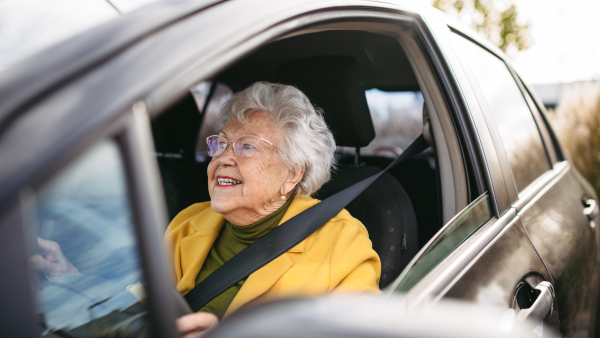 Happy senior woman driving car alone, enjoying the car ride. Safe driving for elderly adults, older driver safety.