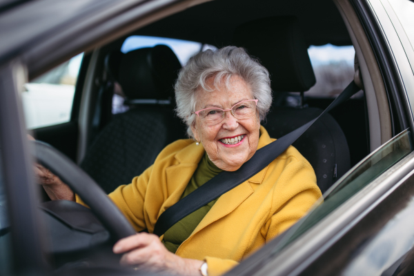 Happy senior woman driving car alone, enjoying the car ride. Safe driving for elderly adults, older driver safety. Driving license renewal at older age.