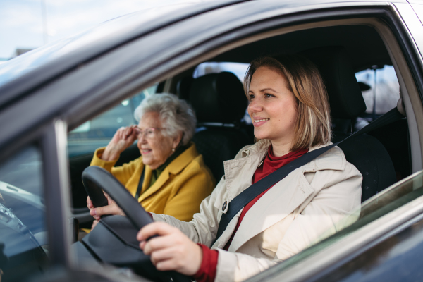 Granddaughter driving her elderly grandmother in the car, taking her to the doctor, shopping or to bank. Caregiver driving elderly lady to the church.