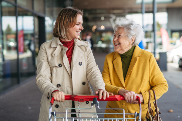 Mature granddaughter taking her grandmother shopping at the shopping center. Senior woman needs help with the grocery shopping.