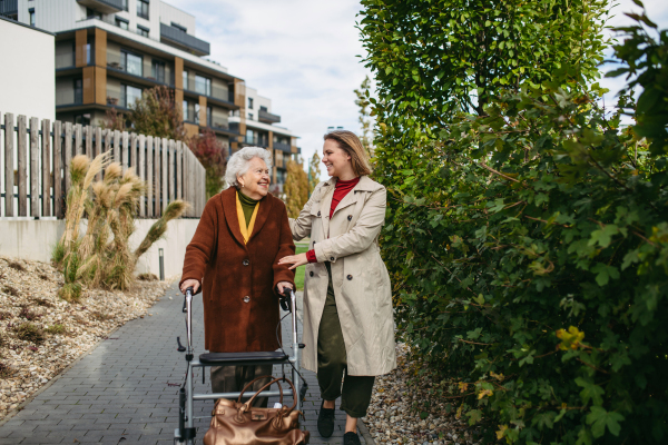 Granddaughter helping her grandmother to fill her prescription medications. Senior woman with a mobility walker and her caregiver leaving pharmacy in city.