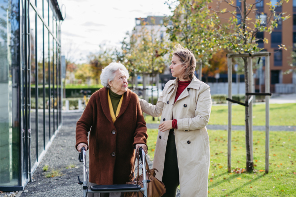 Granddaughter helping her grandmother to fill her prescription medications. Senior woman with a mobility walker and her caregiver leaving pharmacy in city.