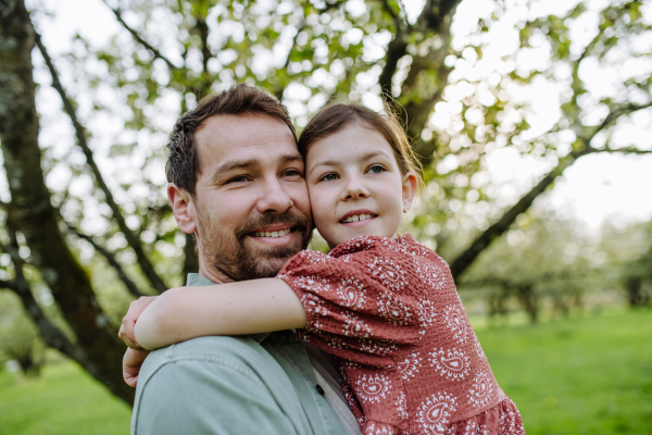 A father hugging his daughter in spring in nature. Father's day concept.