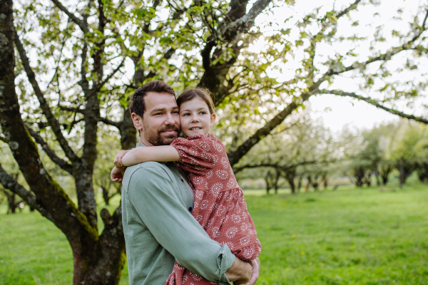 A father hugging his daughter in spring in nature. Father's day concept.