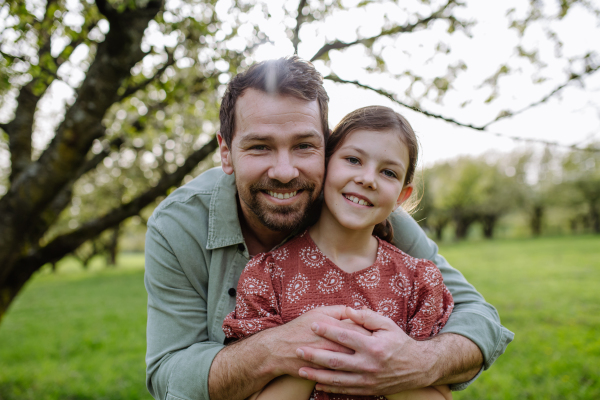 A father hugging his daughter in spring in nature. Father's day concept.