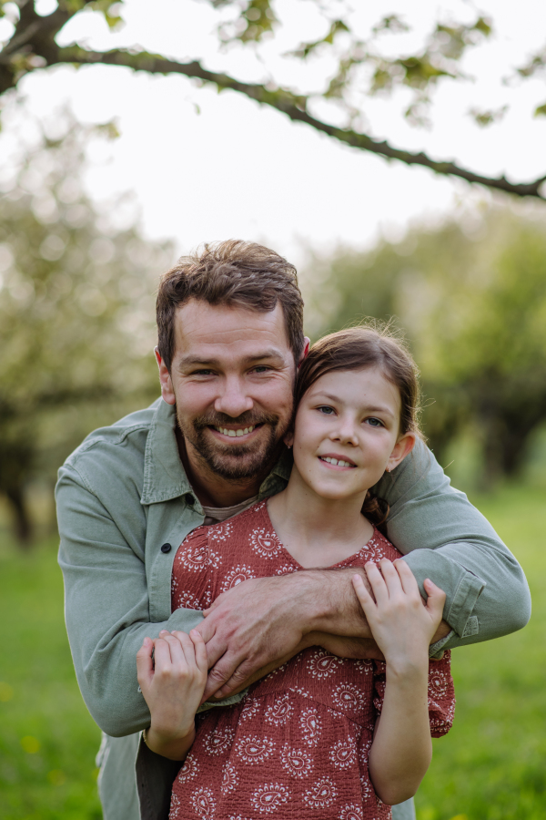 A father hugging his daughter in spring in nature. Father's day concept.