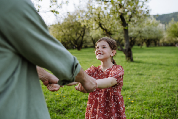 Father spinning daughter around, holding her hands. Dad and girl having fun and laughing outdoor. Father's day concept.