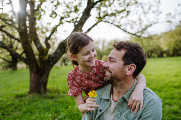 A father looking at daughter lovingly in spring in nature. Father's day concept.