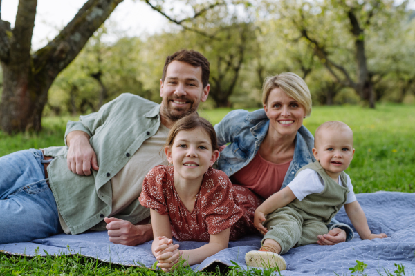 Family portrait with daughter and small toddler or baby, outdoors in spring nature. Nuclear family.