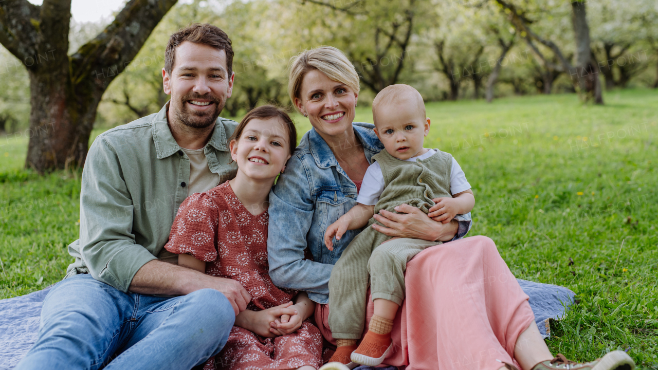 Family portrait with daughter and small toddler or baby, outdoors in spring nature. Nuclear family.