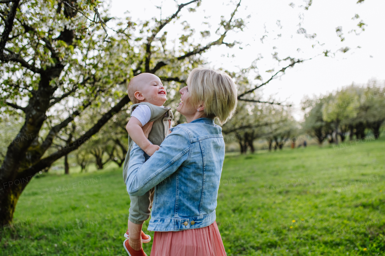 Portrait of beautiful mature first time mother with small toddler, baby, outdoors in spring nature.