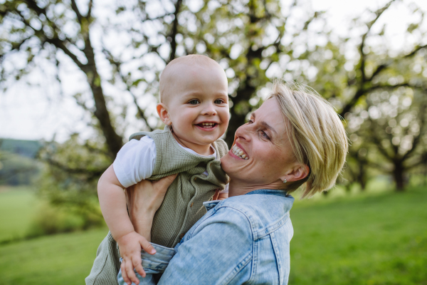 Portrait of beautiful mature first time mother with small toddler, baby, outdoors in spring nature.