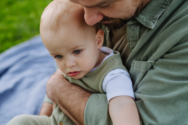 A father holding little baby, playing, having fun during warm spring day. Father's day concept.