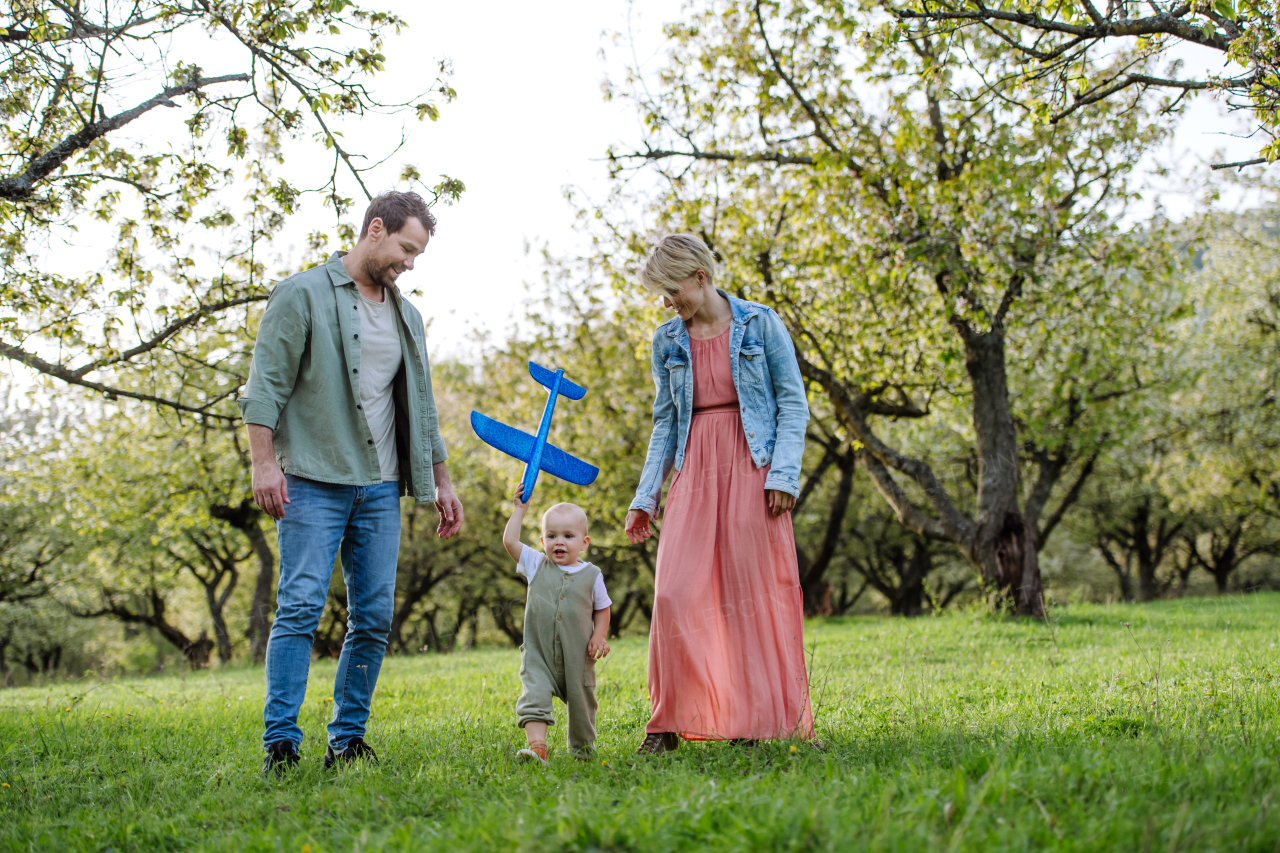 New parents walking with small toddler, baby, outdoors in spring nature. An older first-time parents.