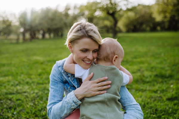 Portrait of beautiful mature first time mother with small toddler, baby, outdoors in spring nature.