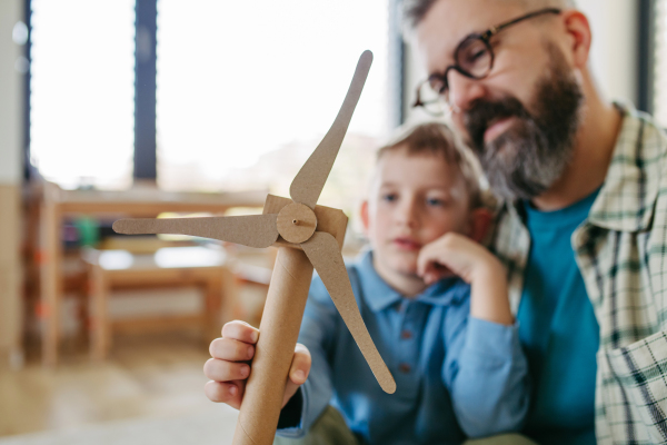 Boy and father holding turbine model. Concpet of renewable energy sustainable lifestyle for next generations. Learning through play.