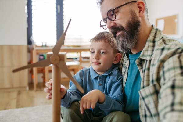 Boy and father holding turbine model. Concpet of renewable energy sustainable lifestyle for next generations. Learning through play.