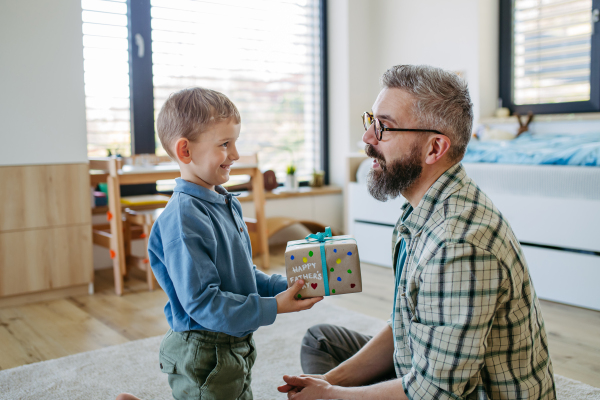 Dad get handmade gift from little son, present wrapped in diy homemade wrapping paper. Happy Fathers day concept.