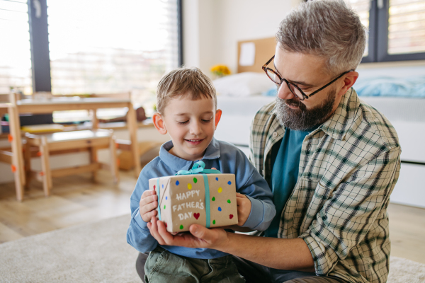 Dad get handmade gift from little son, present wrapped in diy homemade wrapping paper. Close up. Happy Fathers day concept.