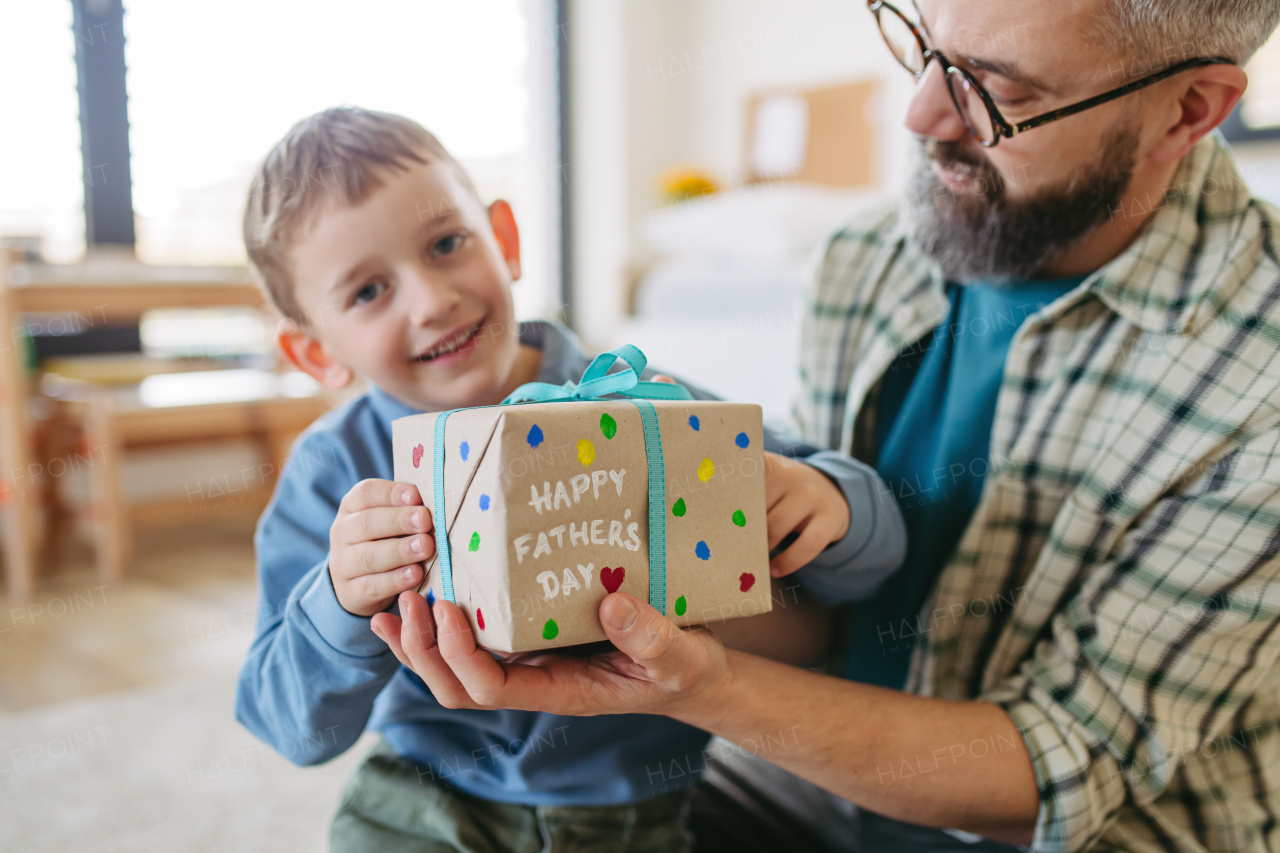 Dad get handmade gift from little son, present wrapped in diy homemade wrapping paper. Close up. Happy Fathers day concept.