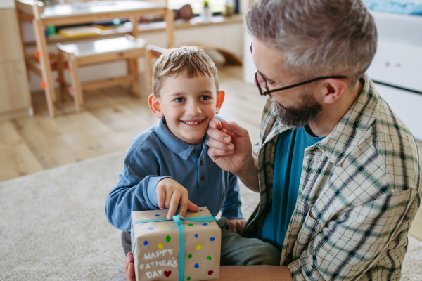 Dad get handmade gift from little son, present wrapped in diy homemade wrapping paper. Close up. Happy Fathers day concept.