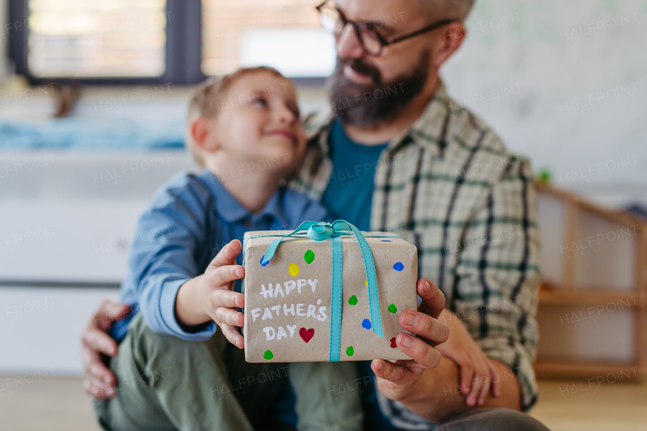 Dad get handmade gift from little son, present wrapped in diy homemade wrapping paper. Close up. Happy Fathers day concept.