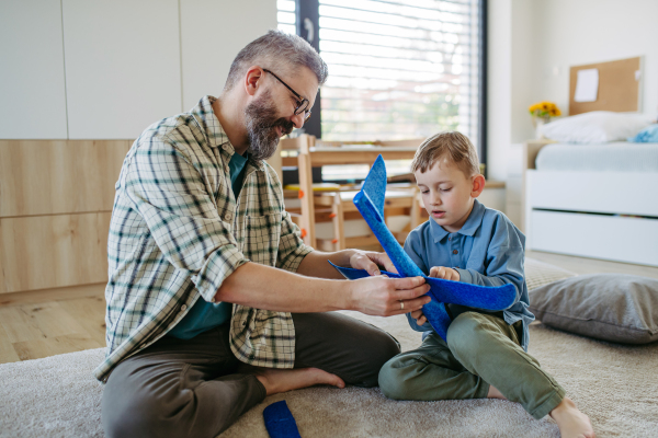 Playing with lightweight styrofoam planes. Playful father and son throwing and flying foam glider planes. Fathers day and parental love concept.