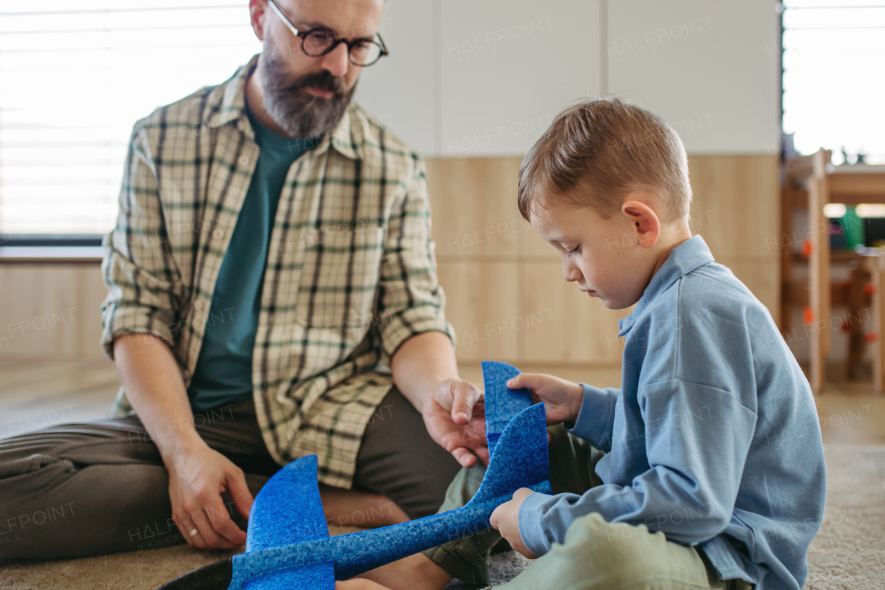 Playing with lightweight styrofoam planes. Playful father and son throwing and flying foam glider planes. Fathers day and parental love concept.