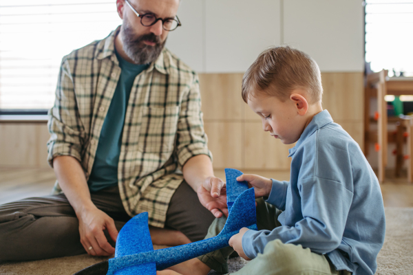 Playing with lightweight styrofoam planes. Playful father and son throwing and flying foam glider planes. Fathers day and parental love concept.