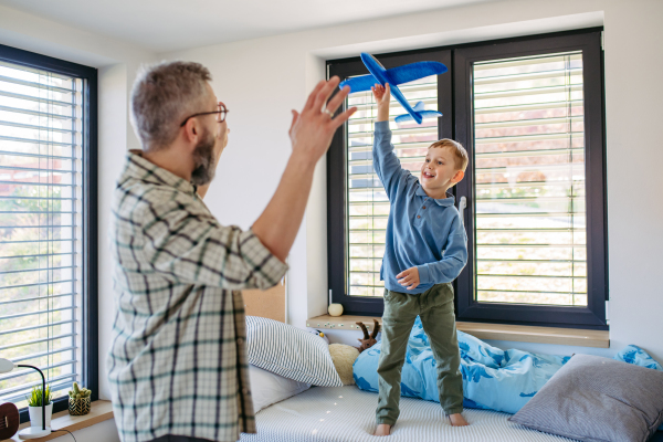 Playing with lightweight styrofoam planes. Playful father and son throwing and flying foam glider planes. Fathers day and parental love concept.