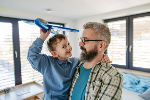 Playing with lightweight styrofoam planes. Playful father and son throwing and flying foam glider planes. Fathers day and parental love concept.