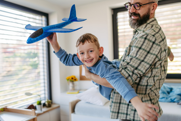 Playing with lightweight styrofoam planes. Playful father and son throwing and flying foam glider planes. Fathers day and parental love concept.