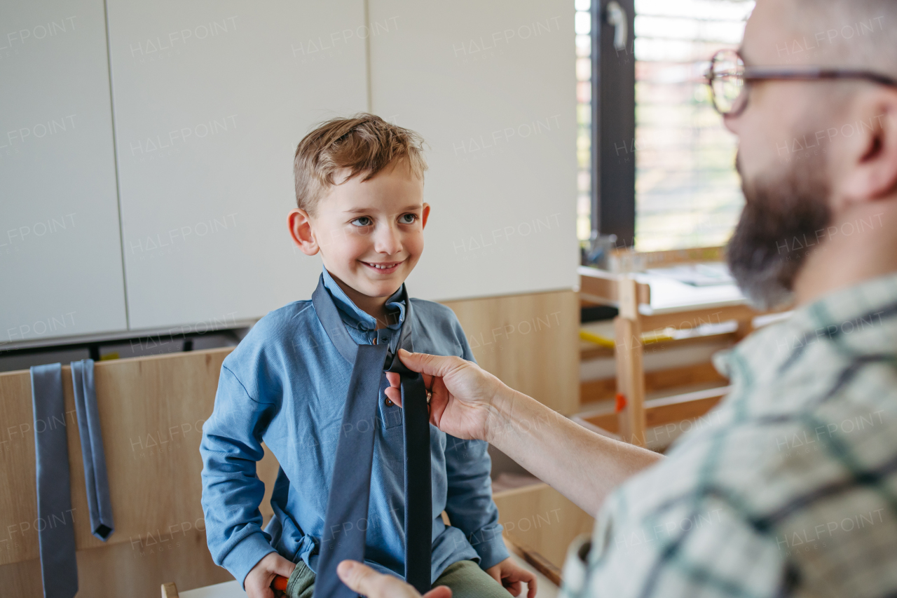 Father teaching son how to tie a tie. Memorable moment for a young boy.