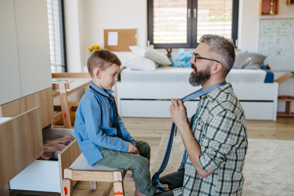 Father teaching son how to tie a tie. Memorable moment for a young boy.