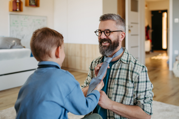 Father teaching son how to tie a tie. Memorable moment for a young boy.