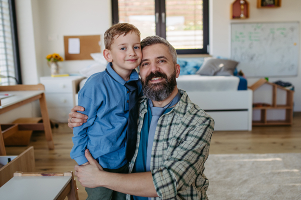 Portrait of dad hugging little son with ties around neck. Teaching how to tie a tie. Happy Fathers day concept.