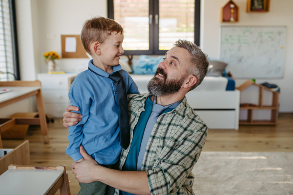 Portrait of dad hugging little son with ties around neck. Teaching how to tie a tie. Happy Fathers day concept.