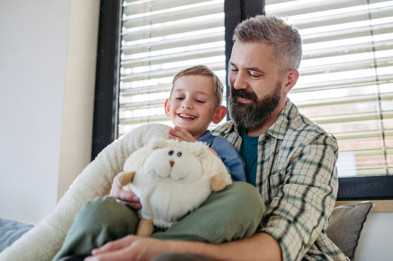 Portrait of smiling boy with father, holding his favourite plush toy. Happy Fathers day concept.