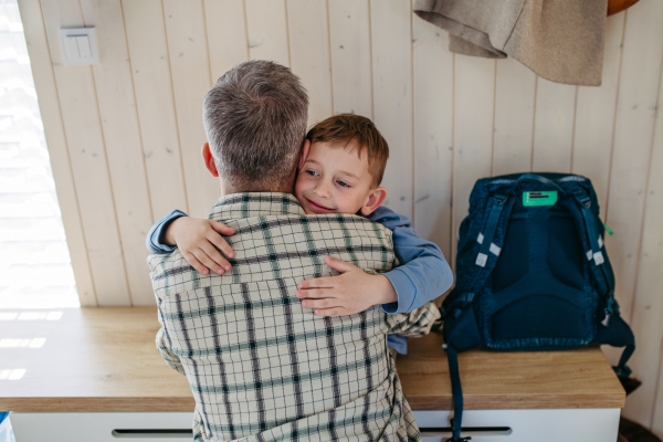 Father helping son get ready for kindergarten, preschool. Huggign each other.