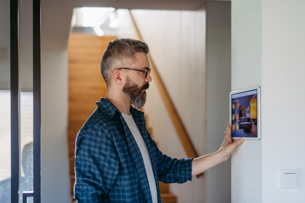 Smart home system. Man adjusting household functions, lighting, security cameras, door locks, smart thermostat or heating settings. Concept of sustainable and smart technology at home.