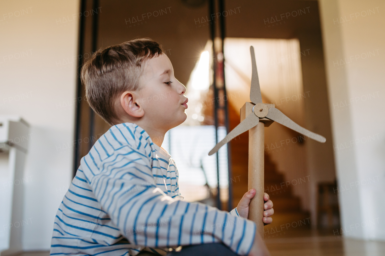 Boy holding turbine model. Concpet of renewable energy sustainable lifestyle for next generations. Learning through play.