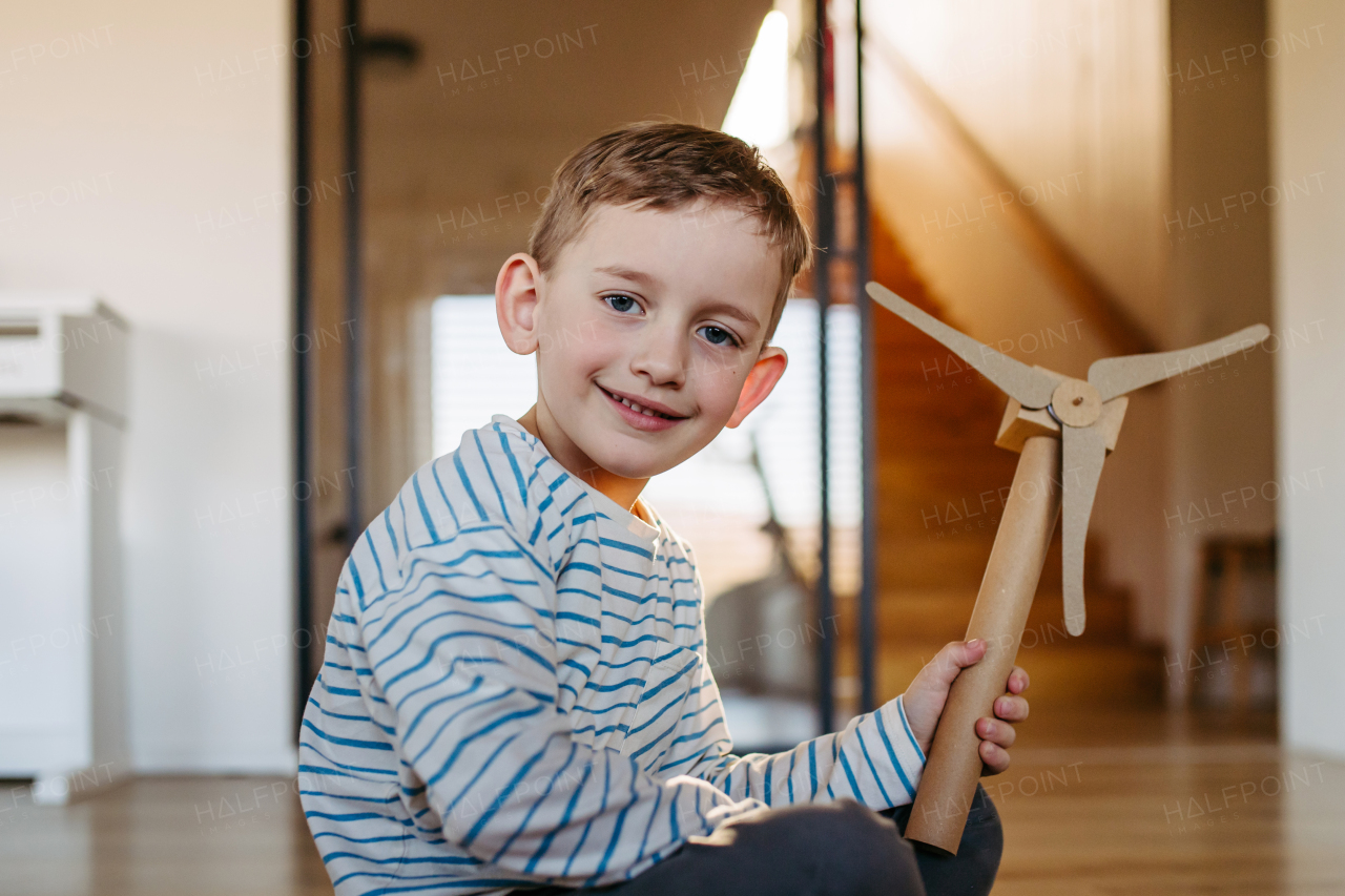 Boy holding turbine model. Concpet of renewable energy sustainable lifestyle for next generations. Learning through play.