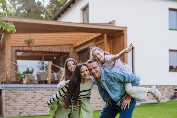 Beautfiul young family standing in front their family home enjoying together time, laughing, having fun.